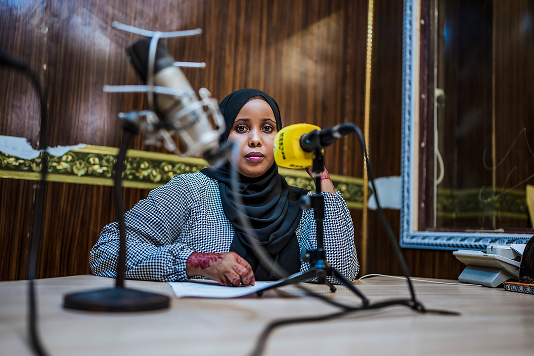 Photo of a Somalian woman surrounded by microphones in a studio
